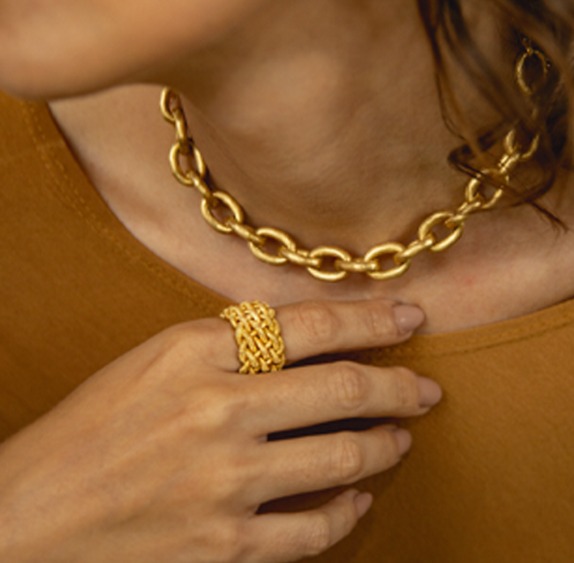 Na foto, a maxi pulseira de elos em ouro amarelo escovado da Coleção Elos e o anel tramado em ouro amarelo escovado da Coleção Day by Day